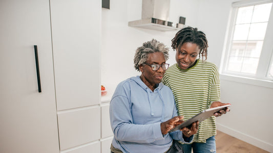 An older woman and younger woman both look at an ipad