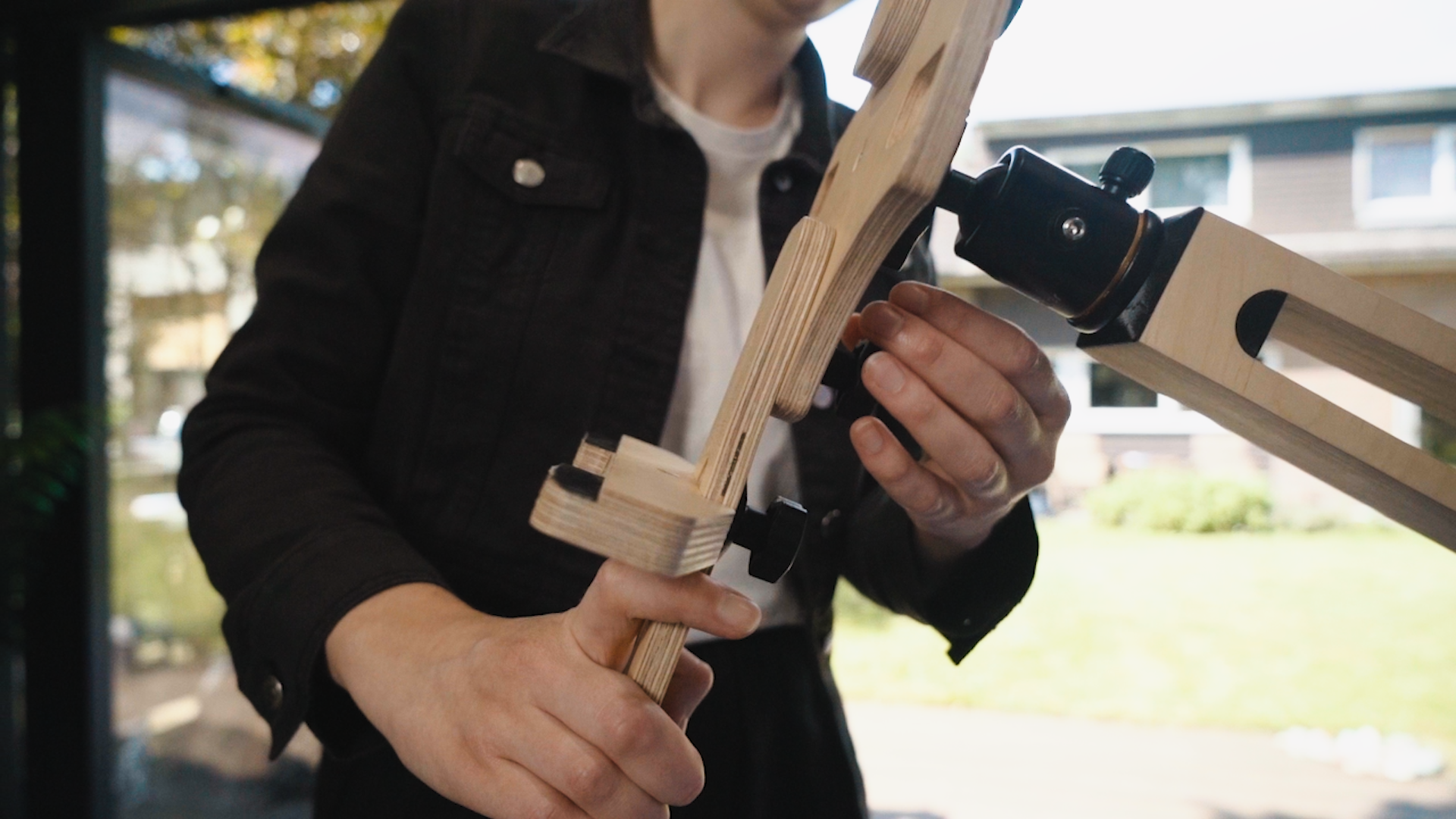 A person's hands are touching the canvas holder of a freasel. The freasel is light wood coloured. They are turning the a black adjustment knob.